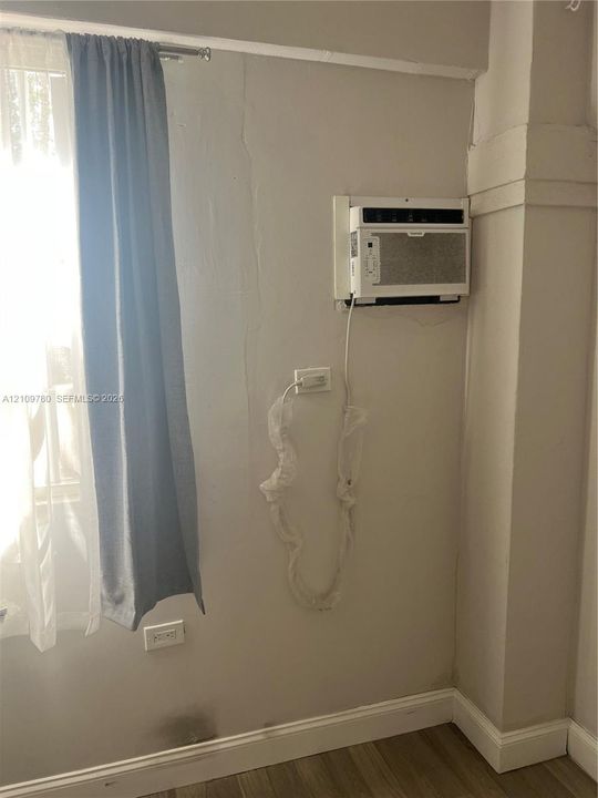 Wall-mounted air conditioning unit, light-toned wall finish, and wood-finish flooring