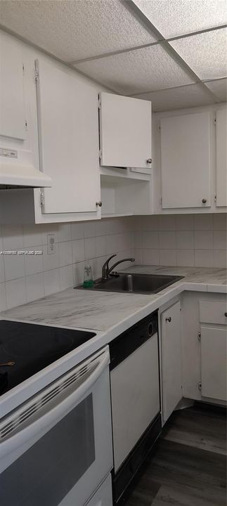 Kitchen featuring white cabinetry, stone-finish countertops, tiled backsplash, stainless steel sink, and wood-finish flooring