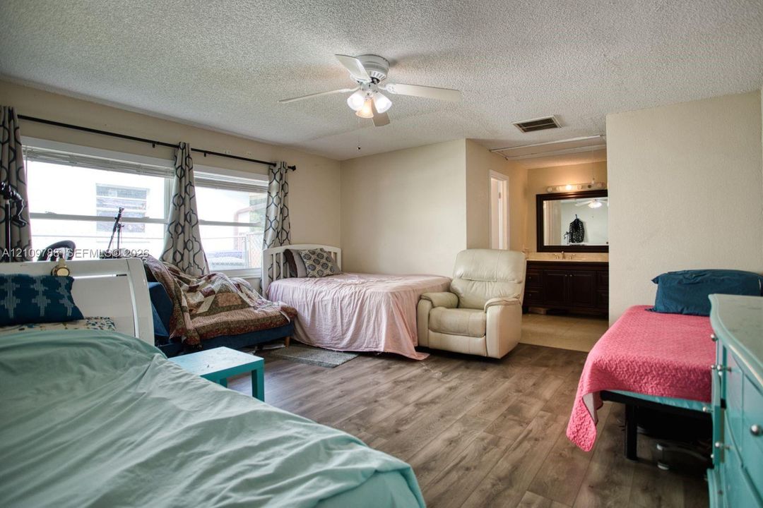 Wood-finish flooring, ceiling fan with integrated lighting, and dark wood cabinetry with vanity mirror