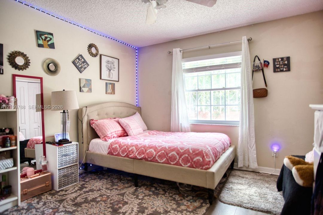 Bedroom with a double-hung window, white-finish ceiling fan, and reach-in closet with sliding doors