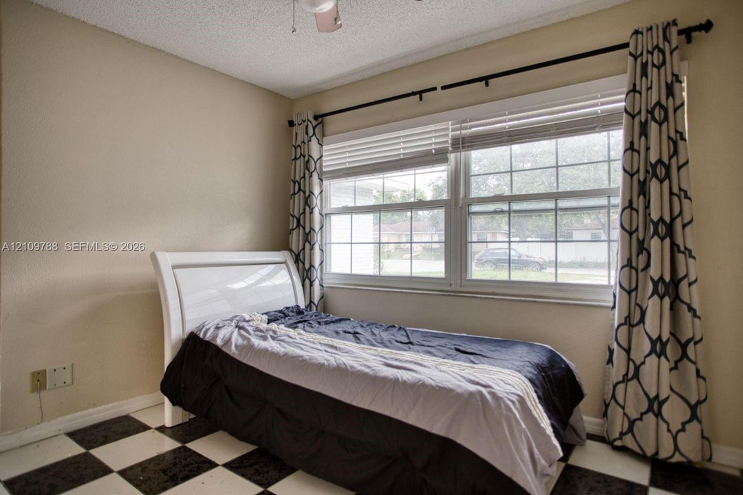 Room featuring grid-patterned tile flooring and horizontal window blinds set within a double-pane window frame