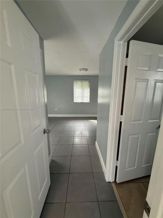 Six-panel interior doors, neutral-toned wall paint, and large-format ceramic tile flooring