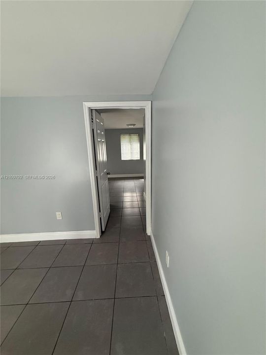 Neutral-toned interior featuring large-format ceramic tile flooring, a six-panel interior door, and a multi-pane window