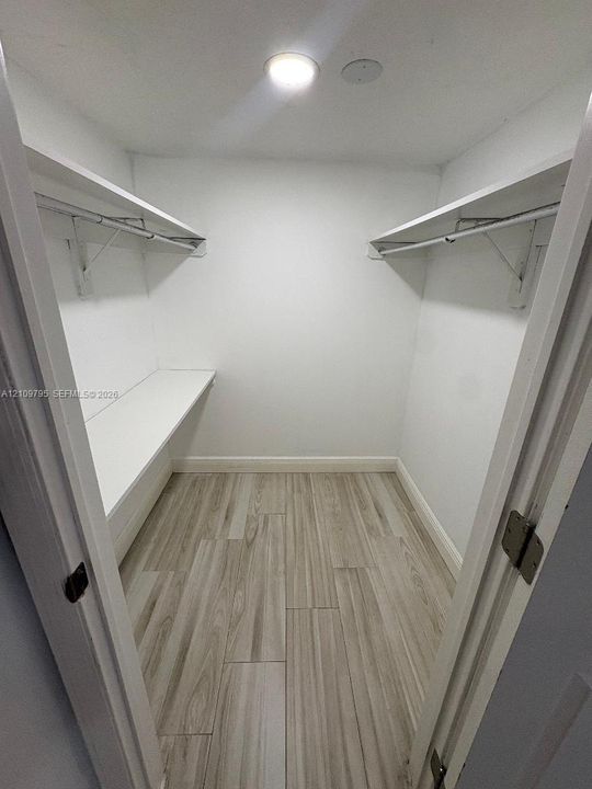Walk-in closet featuring wood-finish flooring, dual levels of built-in shelving, and recessed ceiling lighting