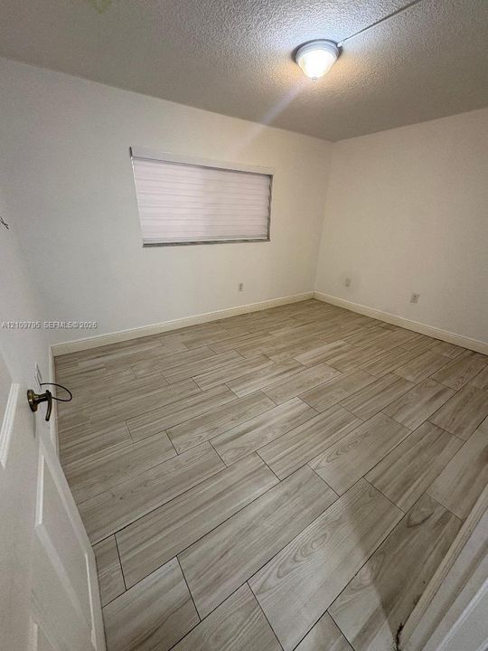 Neutral wall tones, wood-finish flooring, installed horizontal window shades, and flush-mount ceiling lighting