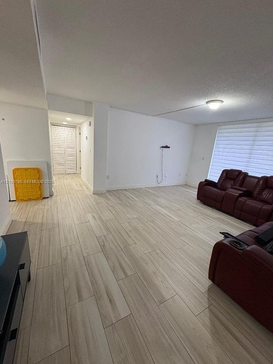 Interior space featuring light-toned wood-finish flooring, white walls, louvered closet doors, and horizontal window blinds