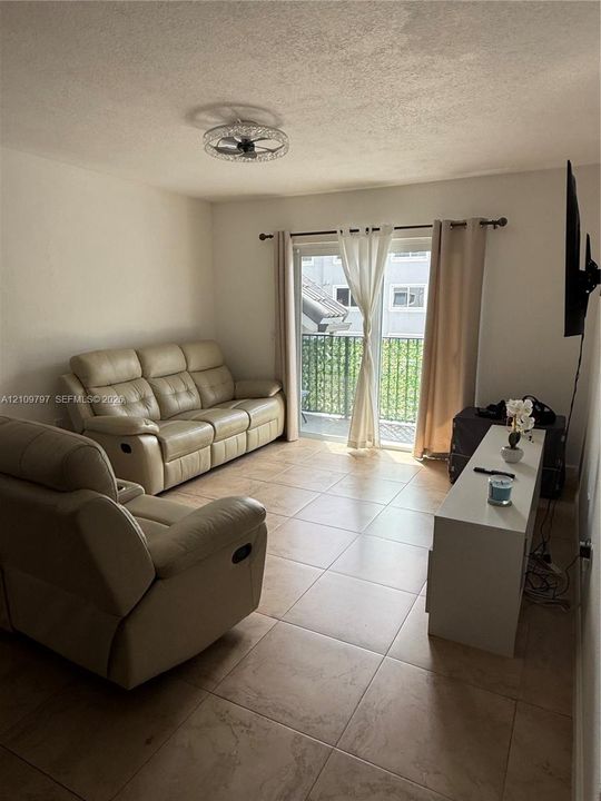 Neutral-toned tile flooring, sliding glass door, and flush-mount ceiling lighting fixture