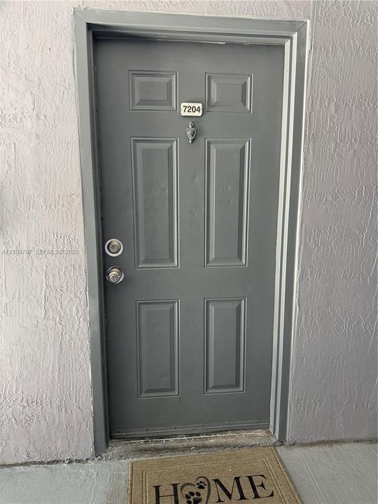 Six-panel grey entry door featuring a brushed metal door knocker, deadbolt, and handle set