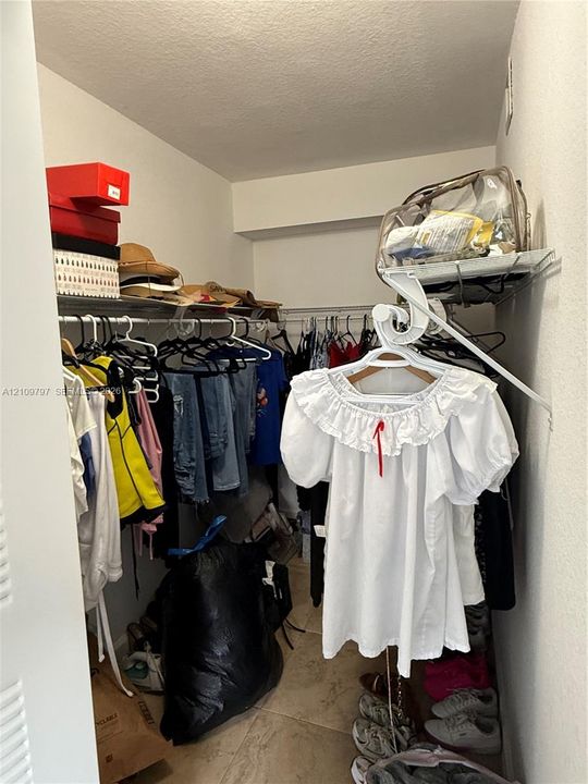 Storage space featuring white wire shelving units and ceramic tile flooring