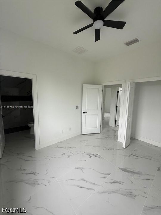 Interior space featuring polished large-format tile flooring, a matte black multi-blade ceiling fan, and solid-core paneled doors with matte black hardware