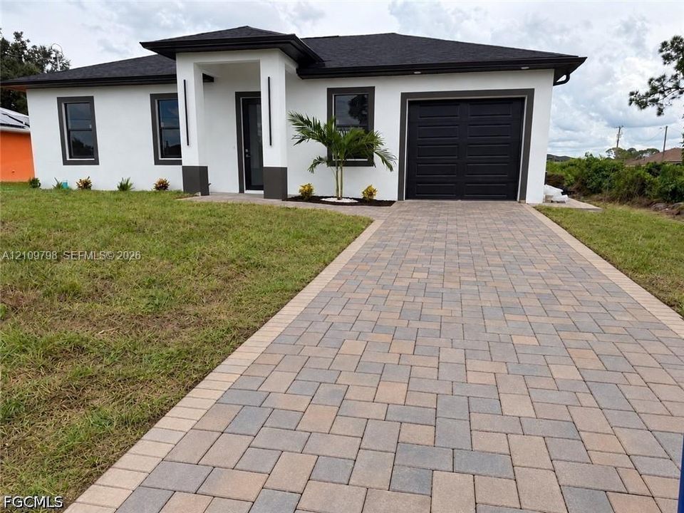 Single-story residence featuring a contemporary exterior, stone-paver driveway, integrated garage, and covered entryway