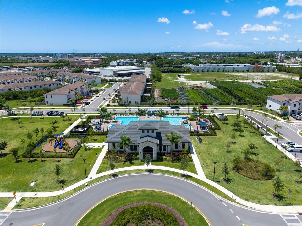 Community clubhouse featuring a swimming pool, surrounding sun deck, and a dedicated playground area situated within landscaped grounds