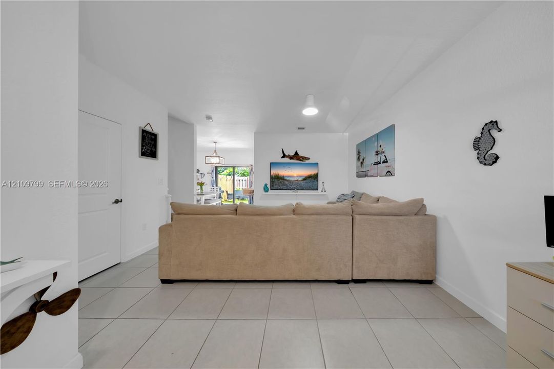 Open-concept interior featuring large-format neutral floor tile, a recessed wall niche, and sliding glass doors