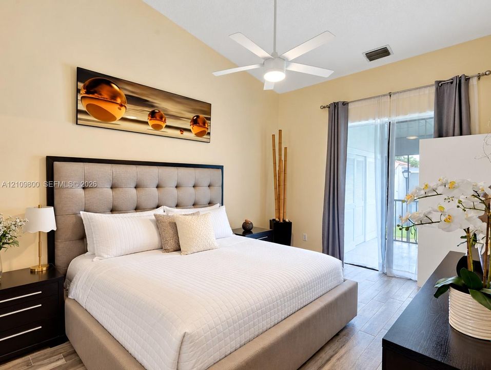 Vaulted ceilings, wood-finish flooring, and glass sliding doors providing exterior access