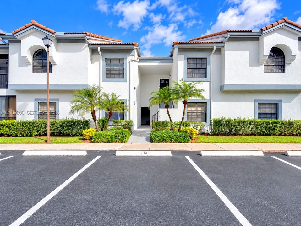 Stucco exterior with multi-pitched tile roofing, arched window detailing, and manicured landscaping