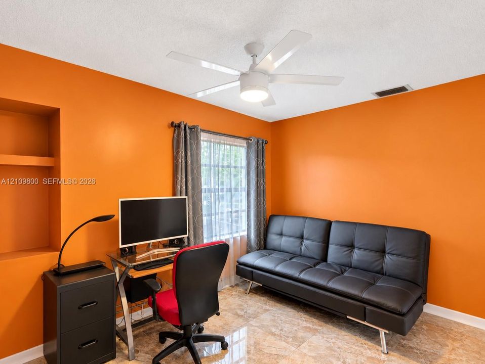 Room featuring a built-in wall niche, tile flooring, and a ceiling-mounted light fixture with a multi-blade fan