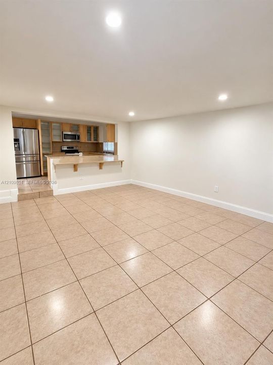 Open-concept area featuring ceramic tile flooring, recessed lighting, and a breakfast bar with stone-finish countertop