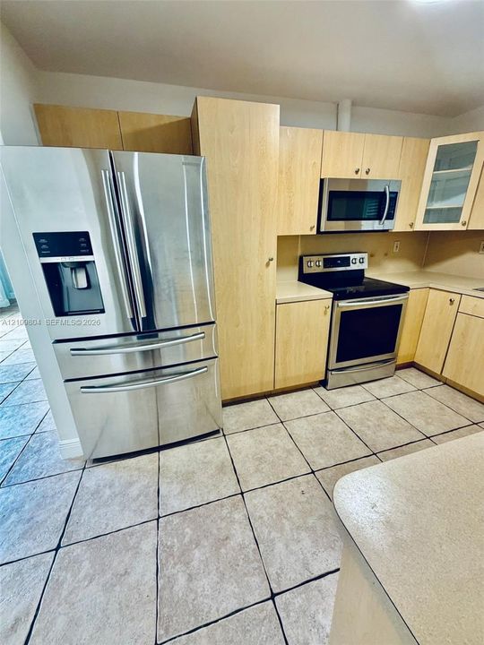 Kitchen featuring light-finish cabinetry, stainless steel French-door refrigerator, stainless steel microwave, stainless steel range, and tile flooring