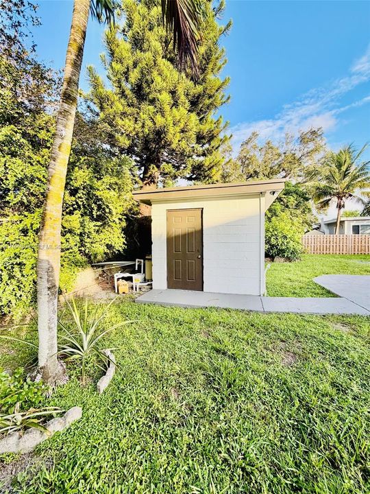 Detached storage structure featuring a concrete block exterior, a single entry door, and a concrete pad foundation