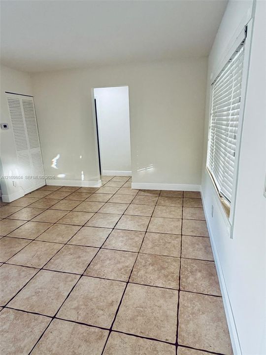 Neutral-toned ceramic tile flooring, horizontal window blinds, and louvered closet doors