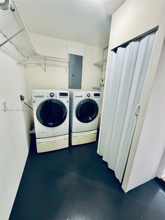 Utility area featuring solid flooring, built-in wire shelving, and a folding privacy door