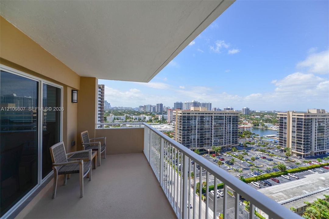Covered balcony featuring concrete flooring, a white metal railing, and wall-mounted exterior lighting