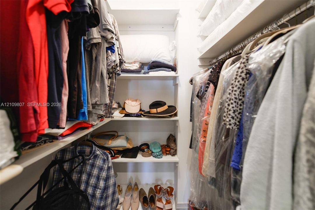 Walk-in closet featuring built-in shelving and dual-level hanging rods