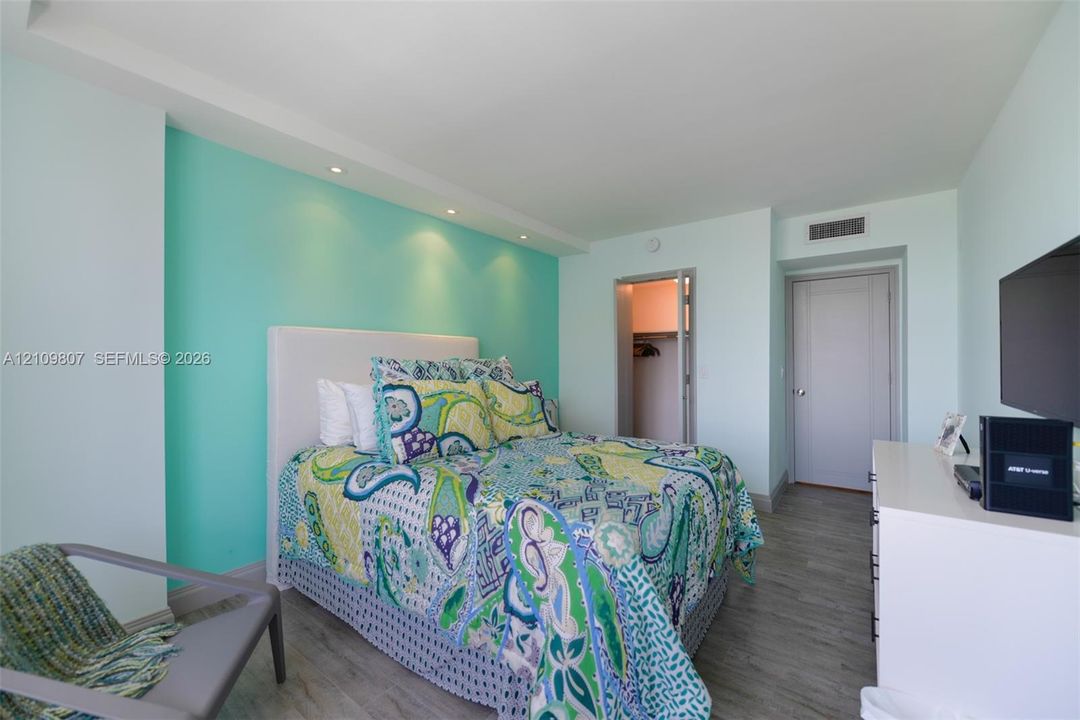 Bedroom featuring wood-finish flooring, recessed lighting, and a walk-in closet with built-in shelving