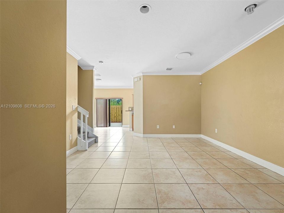 Interior space featuring tile flooring, crown molding, recessed lighting, and a staircase with a white railing