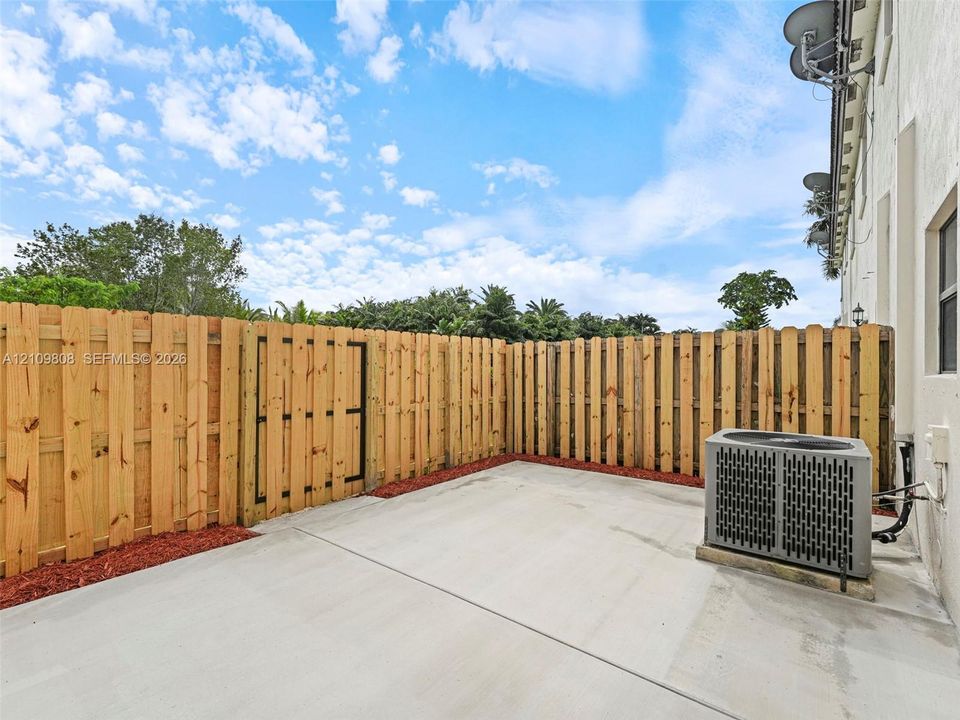 Private fenced courtyard featuring a concrete patio, wood-style privacy fencing, and an integrated gate