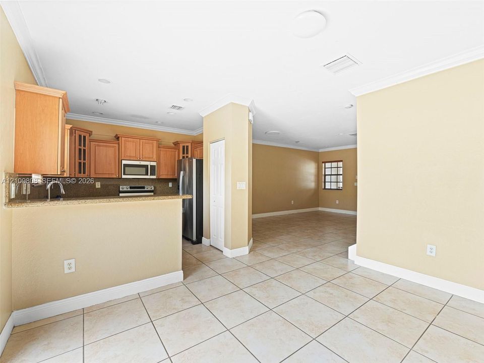 Kitchen featuring light wood cabinetry, stone-finish countertops, stainless steel appliances, and tile flooring