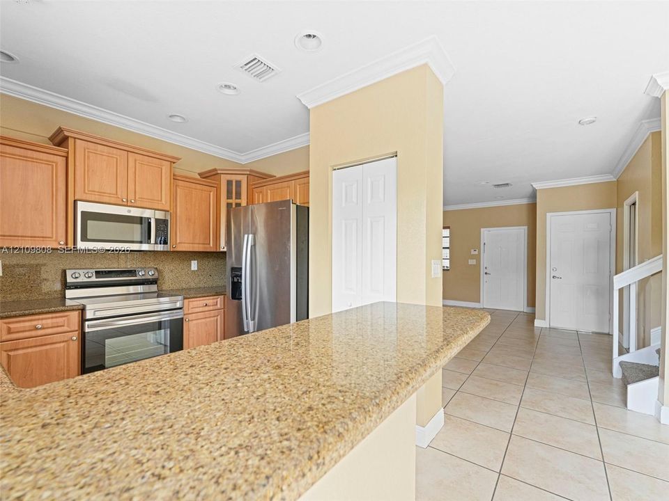 Kitchen featuring wood cabinetry, stone countertops, stainless steel appliances, and ceramic tile flooring