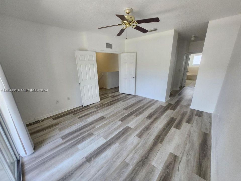 Wood-finish flooring, white panel interior doors, and ceiling fan with integrated lighting