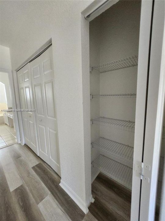 Built-in storage closet featuring wire shelving and multi-panel doors, complemented by wood-finish flooring