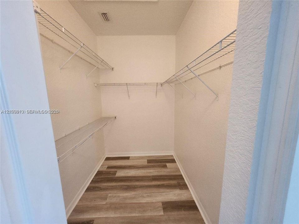 Walk-in storage space featuring wood-finish flooring and tiered wire shelving