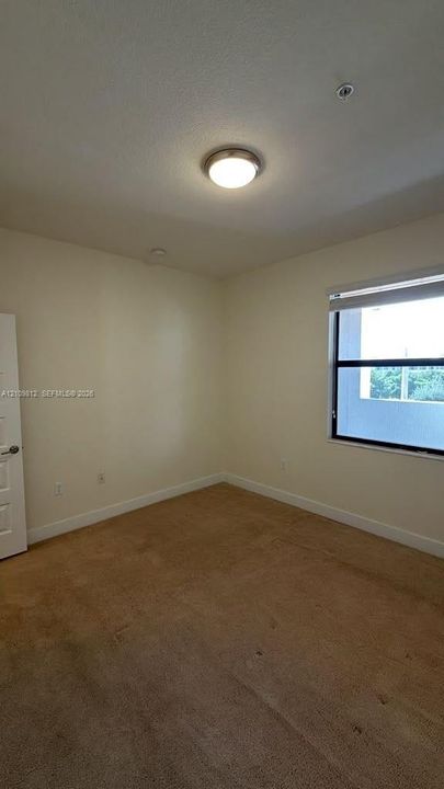Neutral-toned room featuring carpeted flooring, a flush-mount overhead light fixture, and a single-pane window