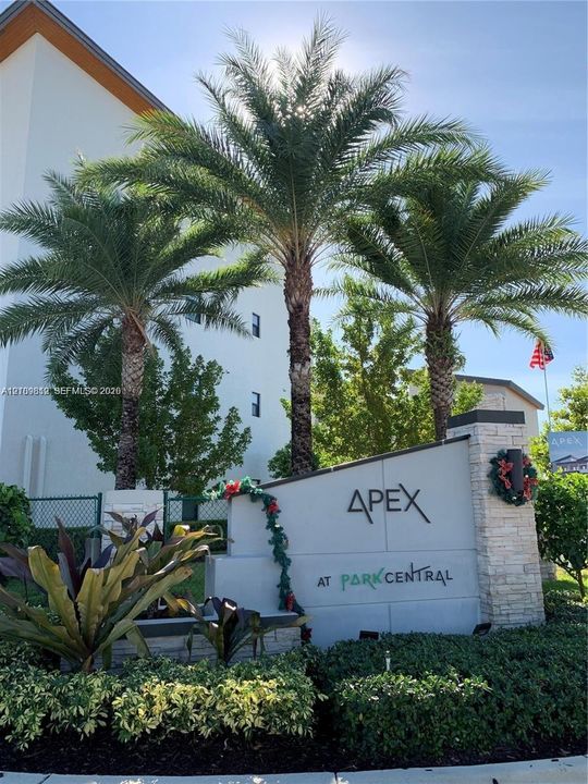 Monument signage featuring stacked stone pillar detailing, integrated landscape lighting, and mature palm tree landscaping