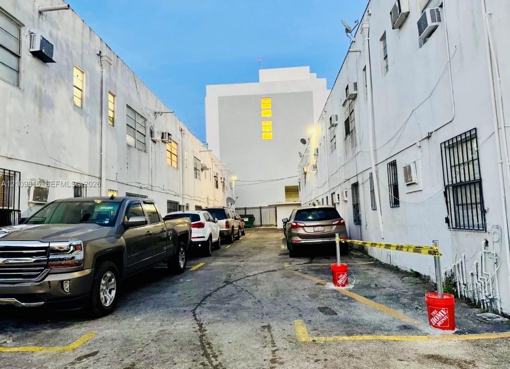 Paved exterior parking area featuring marked spaces and multi-story masonry construction with window security bars