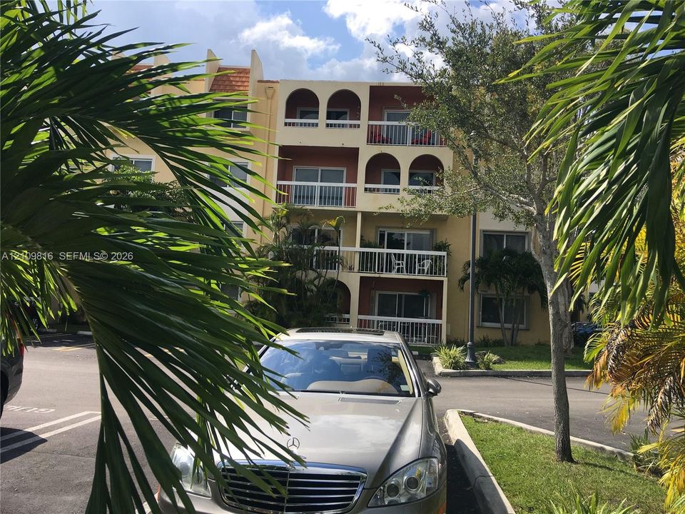 Multi-story stucco exterior featuring arched balcony detailing, white railings, and sliding glass doors