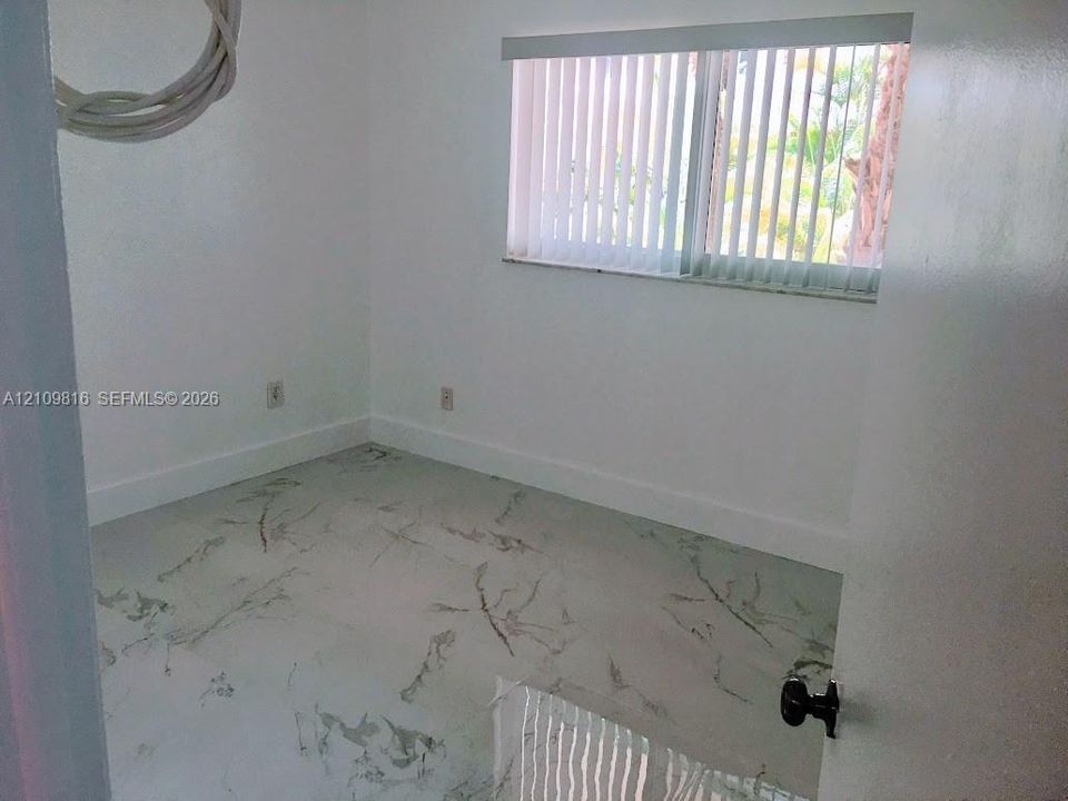 Interior room featuring large-format tile flooring with a neutral stone pattern and vertical window blinds