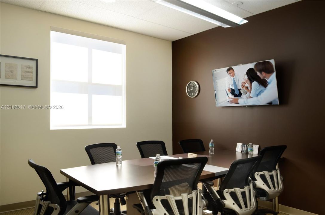 Meeting room featuring a neutral color palette, large window for natural light, and overhead fluorescent lighting