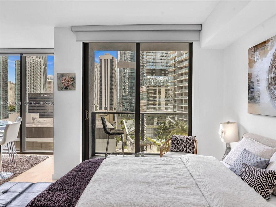 Floor-to-ceiling sliding glass doors, private balcony, wood-finish flooring, and neutral wall color palette
