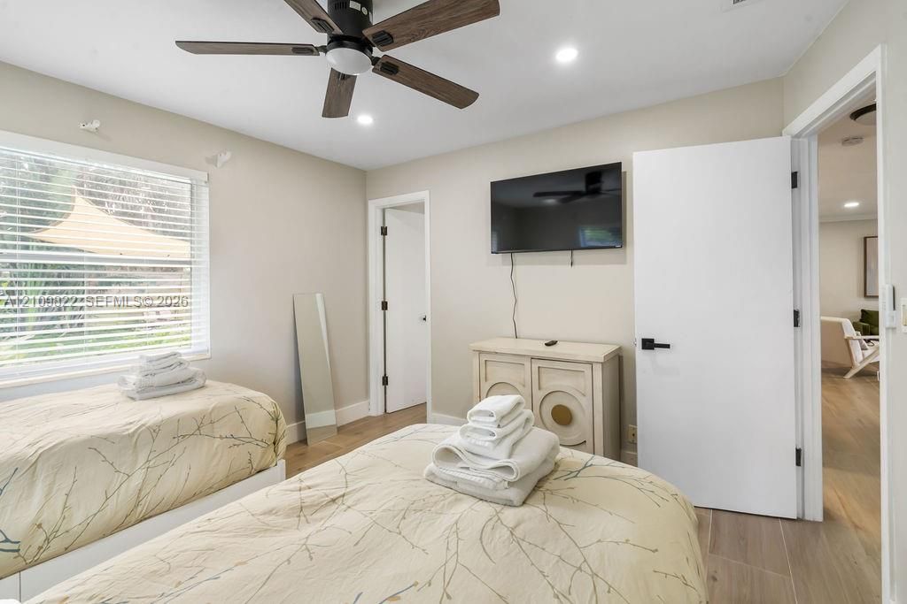 Wood-finish flooring, multi-blade ceiling fan with integrated lighting, recessed lighting, and horizontal slatted window blinds