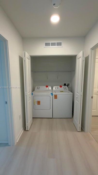 Laundry closet featuring white bi-fold doors and overhead shelving
