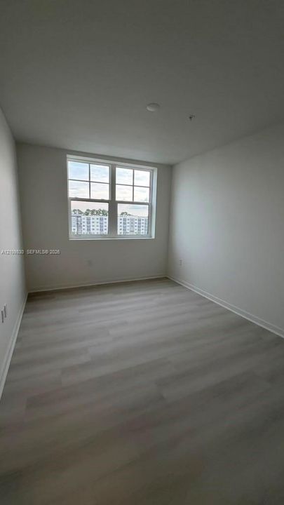 Neutral-toned wood-finish flooring, double-hung divided light window, and smooth-finish walls