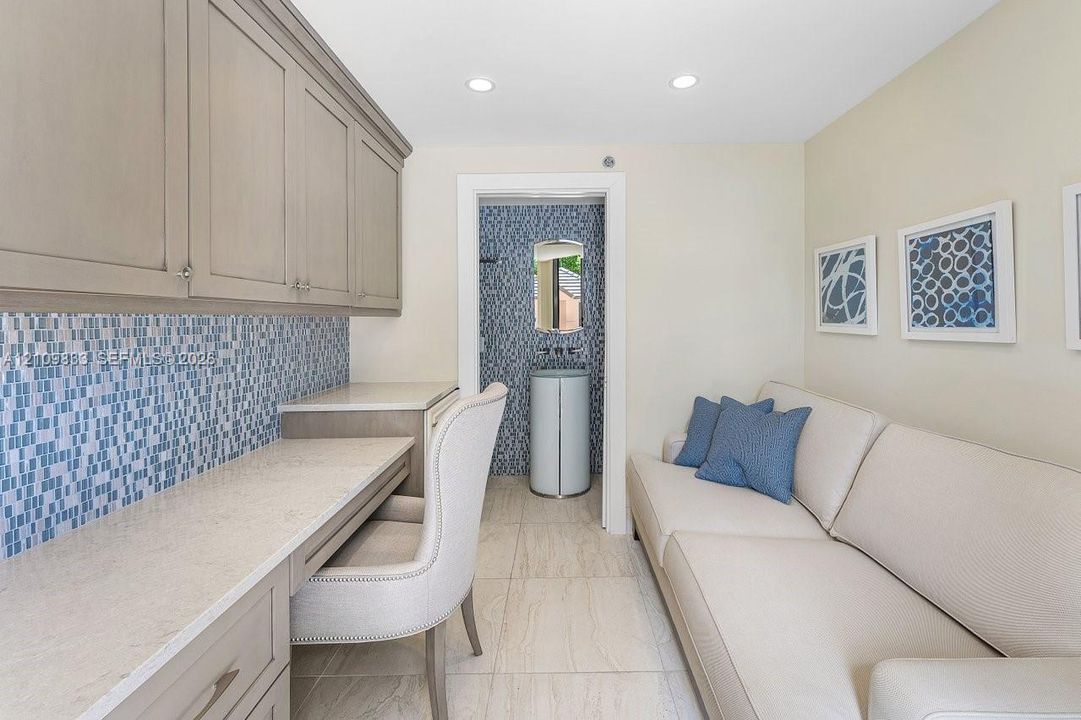 Built-in desk with neutral stone countertop, blue mosaic tile backsplash, recessed ceiling lighting, and tile flooring