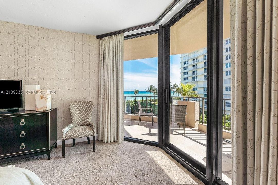 Floor-to-ceiling sliding glass doors, private balcony with metal railing, and patterned wall covering