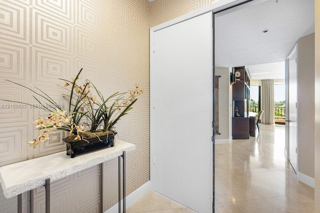Entryway featuring geometric patterned wall coverings, stone-finish flooring, and a sliding door