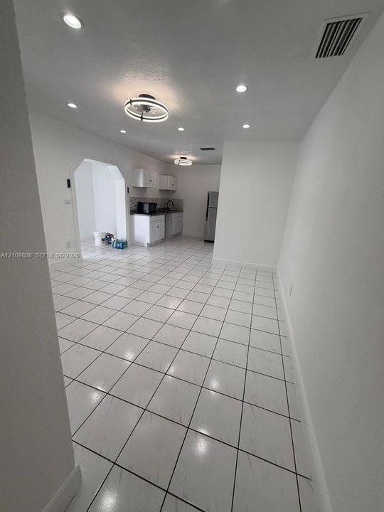 Large-format ceramic tile flooring with white cabinetry, built-in recessed lighting, decorative flush-mount light fixtures, and a cased opening