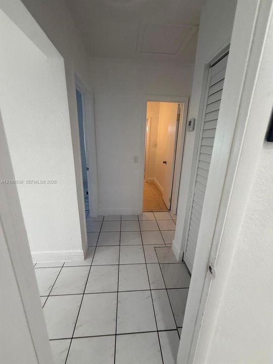 Interior hallway featuring white tile flooring and louvered bi-fold closet doors
